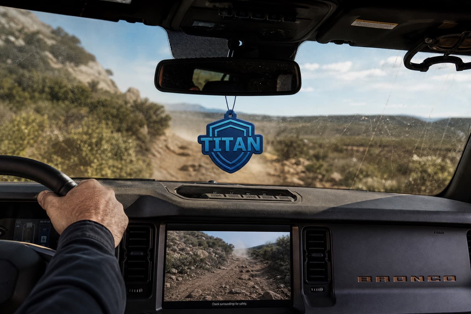 A branded hanging air freshener in the cab of a truck on a back road